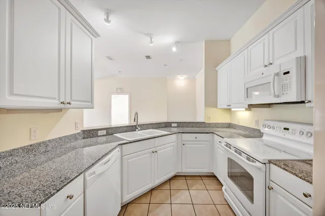 a kitchen with stainless steel appliances granite countertop a sink a stove and white cabinets