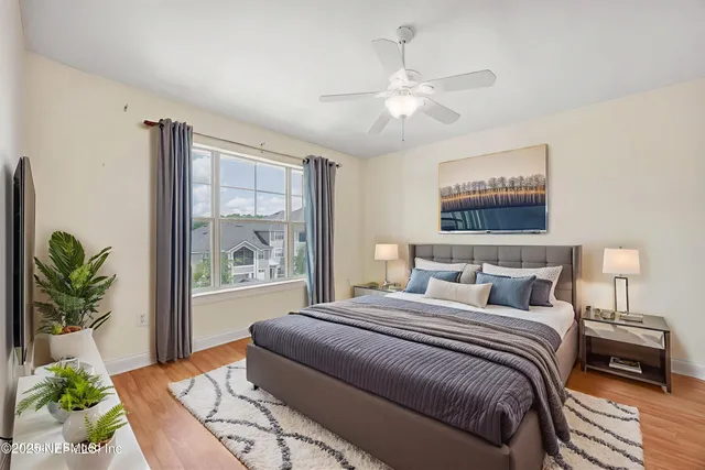 an empty room with wooden floor chandelier fan and windows