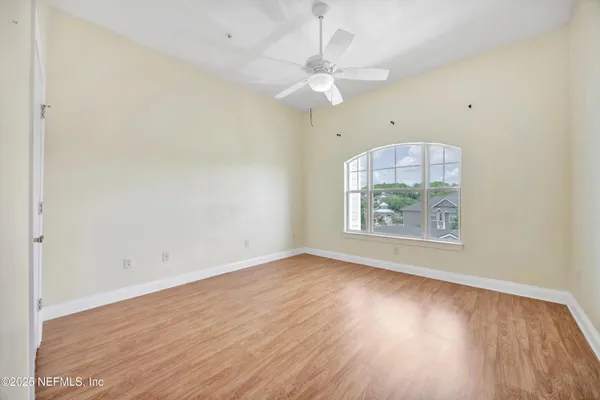 an empty room with wooden floor and fan
