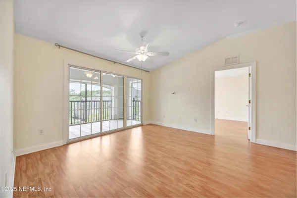 a view of an empty room with wooden floor and a window