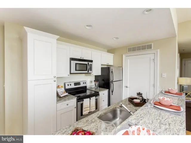 a kitchen with stainless steel appliances kitchen island granite countertop a sink stove and refrigerator