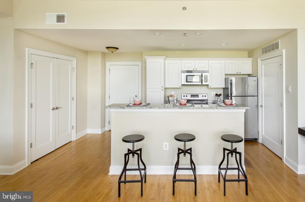 230-38 North 21st Street, Unit 604 Philadelphia, PA 19103 - Photo 4 of 20 a kitchen with stainless steel appliances a dining table chairs and wooden floor