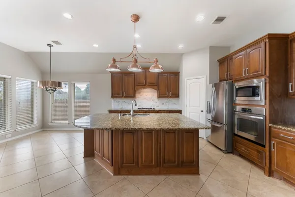 a kitchen with granite countertop kitchen island stainless steel appliances a refrigerator sink and microwave