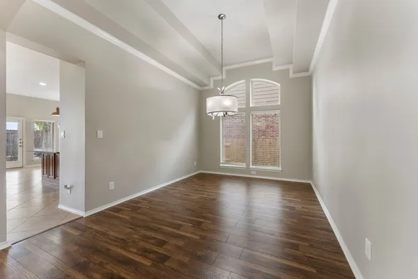 a view of an empty room with kitchen and chandelier fan