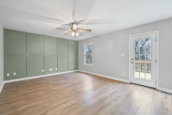 a view of an empty room with a window and wooden floor