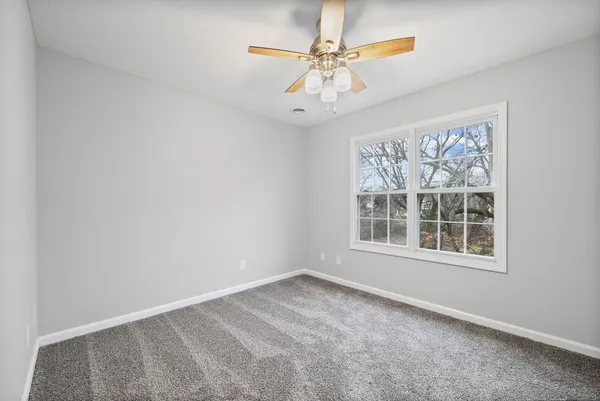 an empty room with windows and fan