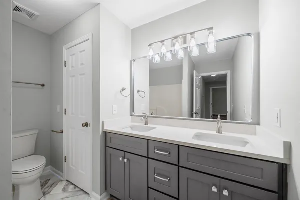 a bathroom with a double vanity sink toilet and mirror