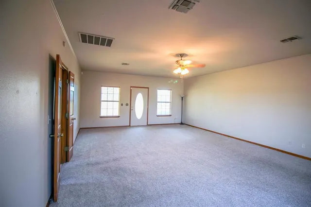 a view of a big room with windows and chandelier fan
