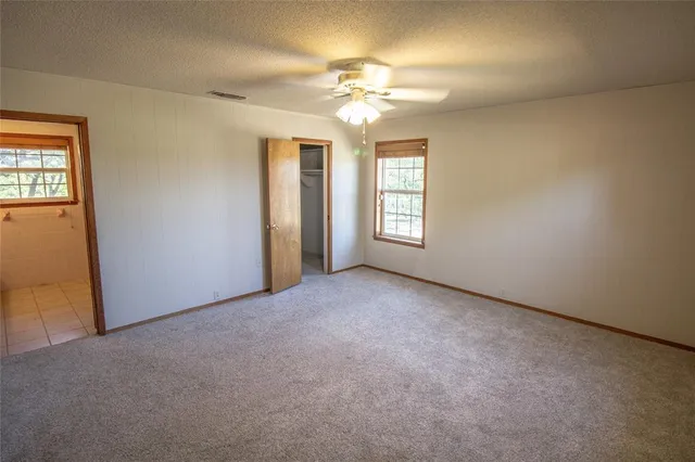 an empty room with windows and chandelier fan