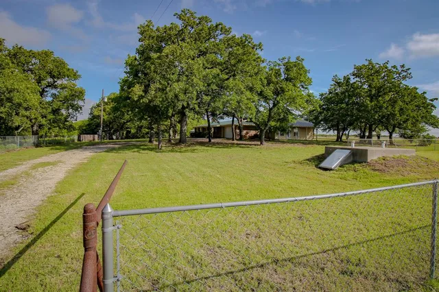 a view of a backyard with wooden fence and large trees