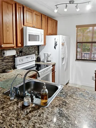 a kitchen with stainless steel appliances a sink a stove a refrigerator cabinets and a window