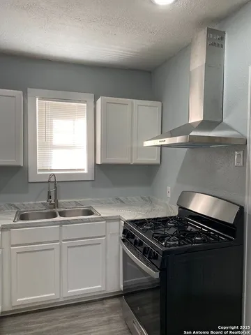 a kitchen with granite countertop a sink stove and cabinets