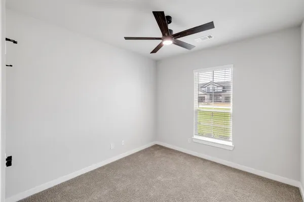 an empty room with windows and fan
