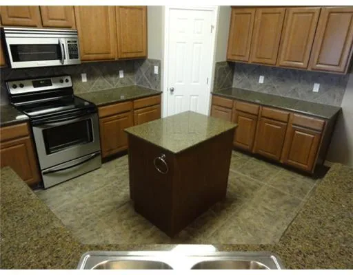 a kitchen with stainless steel appliances granite countertop a stove a sink and a microwave