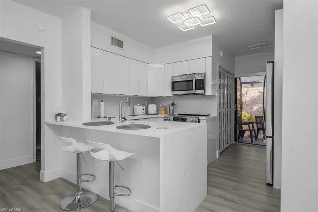 a kitchen with kitchen island granite countertop stainless steel appliances a sink a stove a refrigerator cabinets and dining table