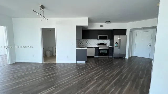 a view of kitchen with stainless steel appliances granite countertop a refrigerator and a stove top oven