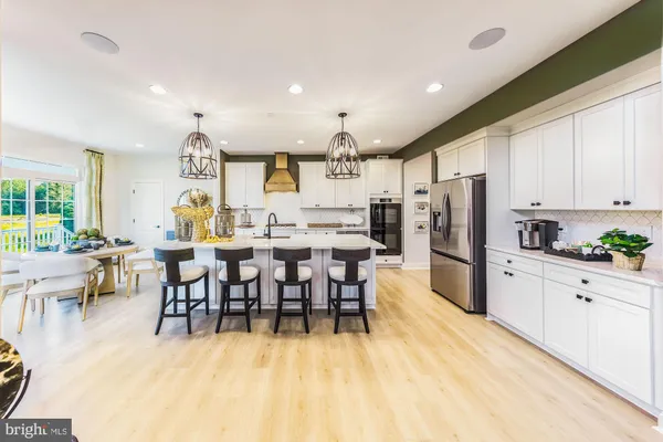 a kitchen with stainless steel appliances a dining table chairs refrigerator and sink