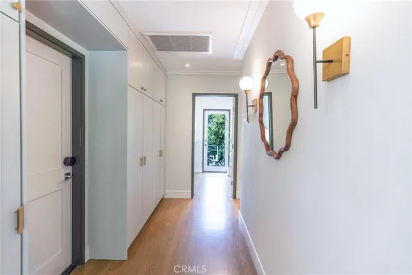 a view of a hallway with wooden floor and mirror