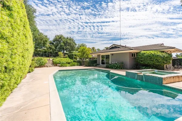 a view of swimming pool with lawn chairs and plants