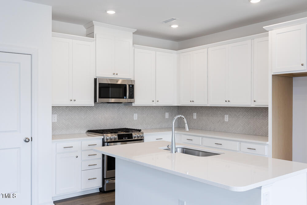 161 Charlie Smith Road Angier, NC 27501 - Photo 5 of 57 a kitchen with white cabinets and stainless steel appliances