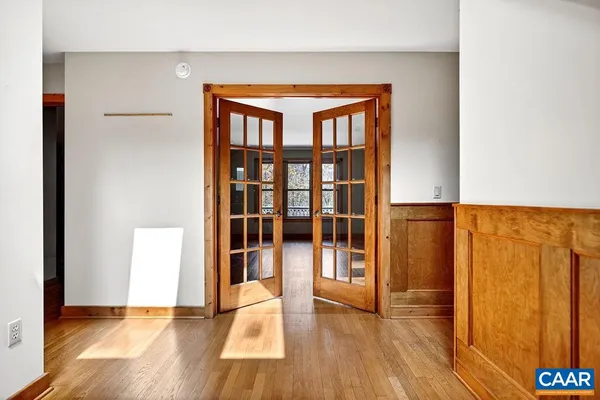 a view of an empty room with wooden floor and a window