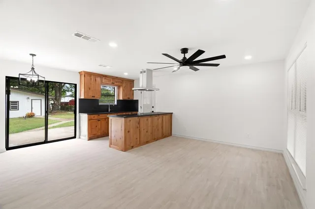 a living room with stainless steel appliances kitchen island granite countertop a refrigerator a sink a stove a microwave oven and a window