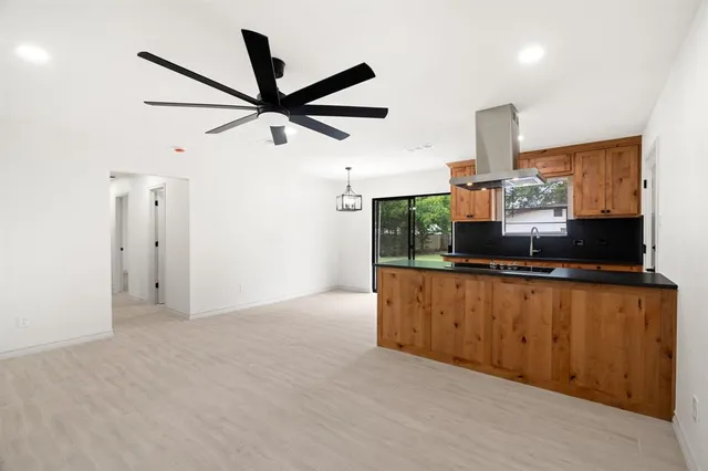 a living room with stainless steel appliances kitchen island granite countertop a refrigerator a sink a stove a microwave oven and a window