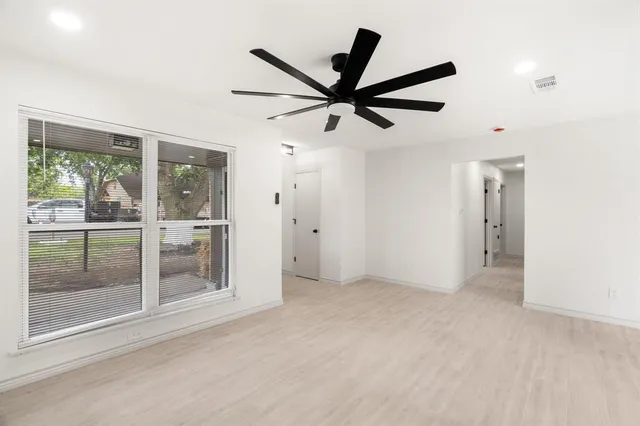 an empty room with a window and a fan