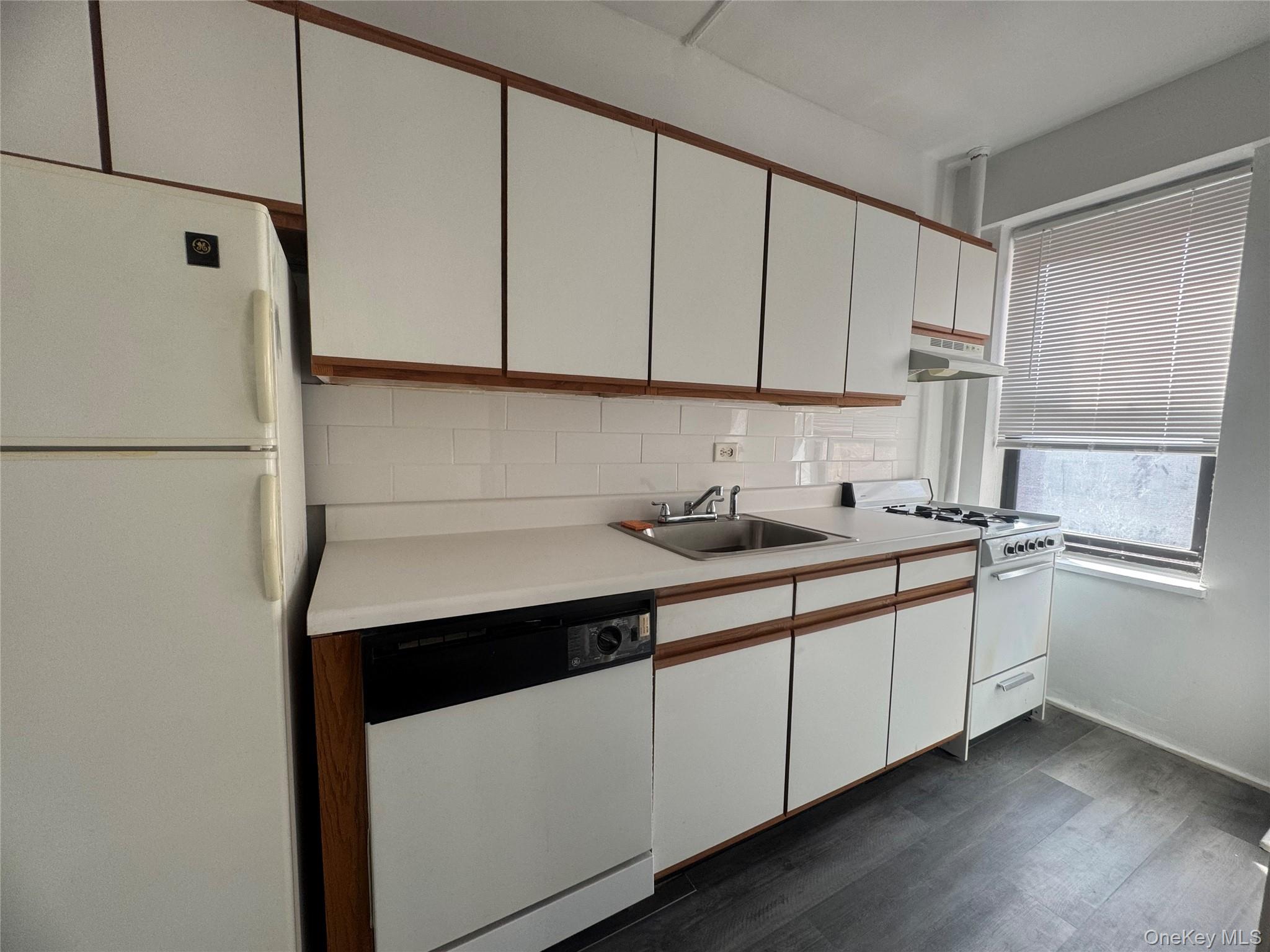 99-21 67th Road, Unit 7K Queens, NY 11375 - Photo 8 of 10 a kitchen with sink cabinets and white appliances