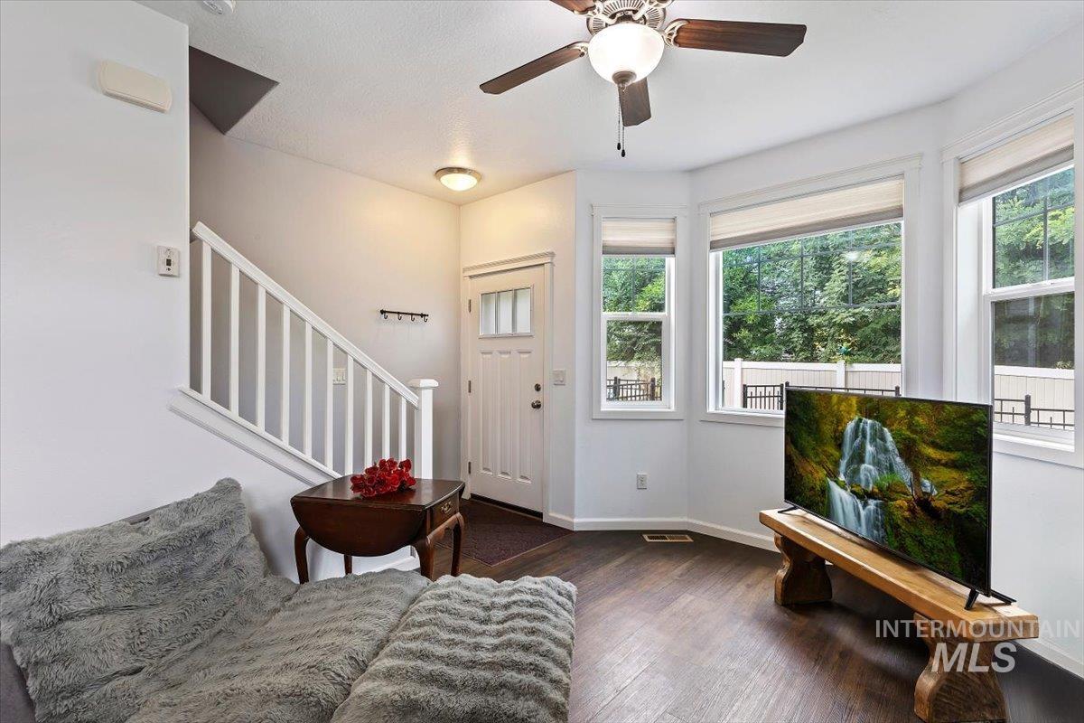 4390 North Five Mile Road Boise, ID 83704 - Photo 4 of 23 Bay window with multiple panes, wood-finish flooring, ceiling fan with integrated lighting, white paneled entry door, and staircase with white railing