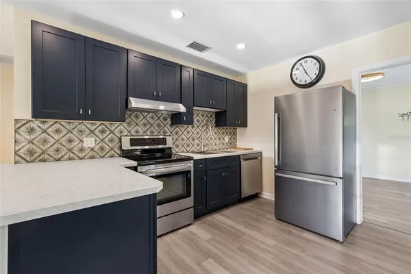 a kitchen with granite countertop a refrigerator stove and wooden floor