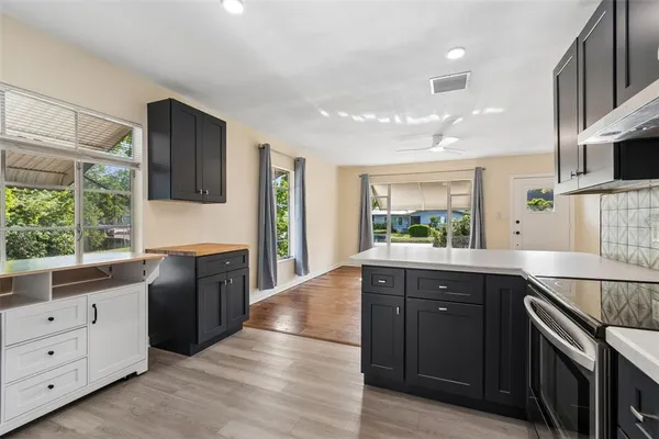 a kitchen with stainless steel appliances granite countertop a refrigerator a sink dishwasher a stove and white countertops with wooden floor