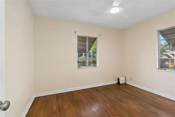 an empty room with wooden floor and windows
