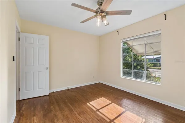 a view of empty room with wooden floor and fan