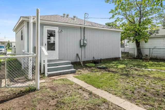 a view of a house with a small yard and large tree