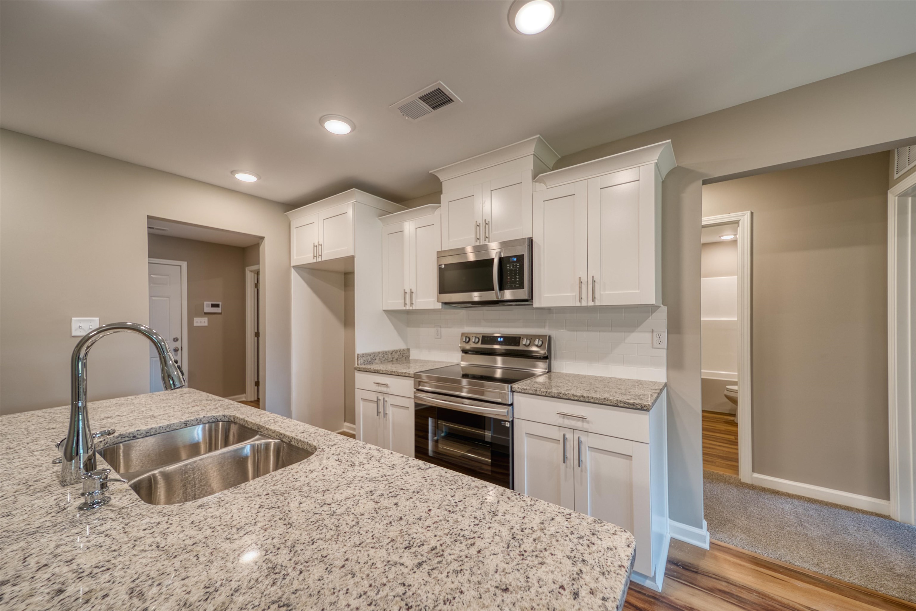 109 Walnut Ridge Ripley, TN 38063 - Photo 25 of 39 Kitchen with stainless steel appliances, wood finished floors, white cabinetry, light stone countertops, and recessed lighting
