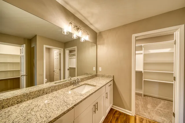 a bathroom with a granite countertop sink and a large mirror