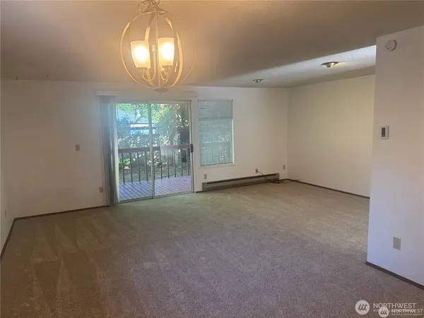 an empty room with a chandelier fan and wooden floor