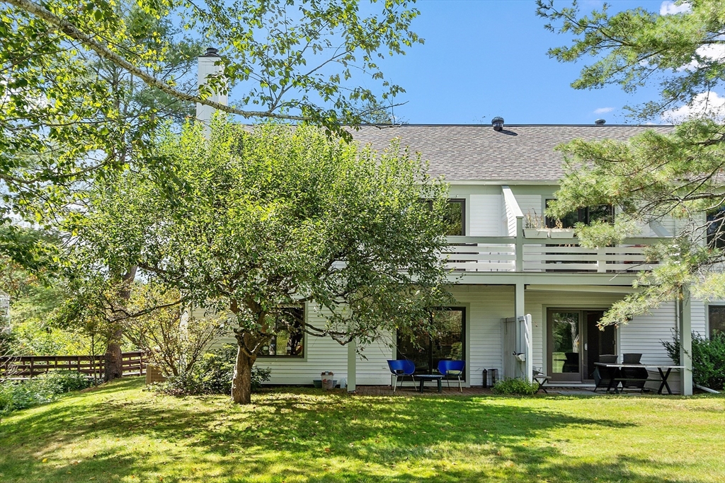 1 Concord Greene, Unit 7 Concord, MA 01742 - Photo 11 of 31 a view of a white house with large trees and a yard with plants