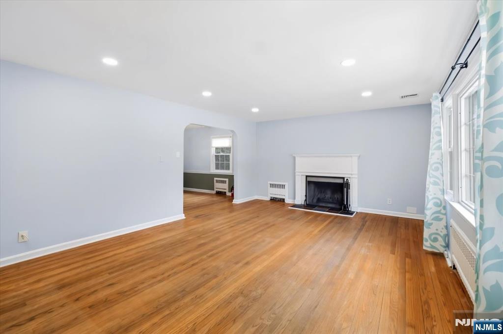 922 Wildwood Road Oradell, NJ 07649 - Photo 9 of 42 an empty room with wooden floor fireplace and windows