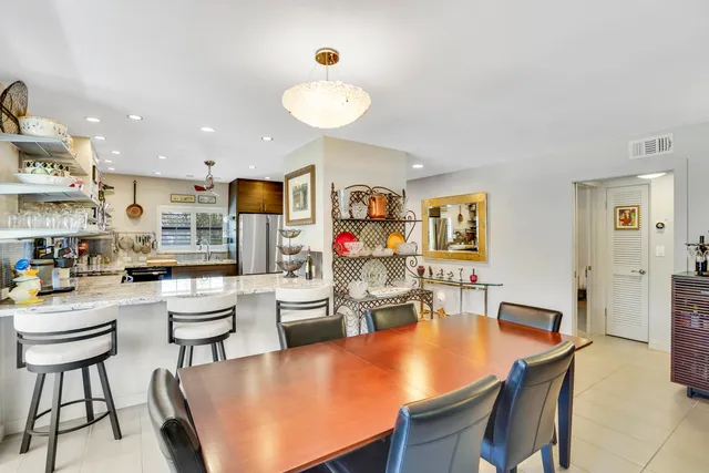 a living room with stainless steel appliances furniture a rug and a kitchen view