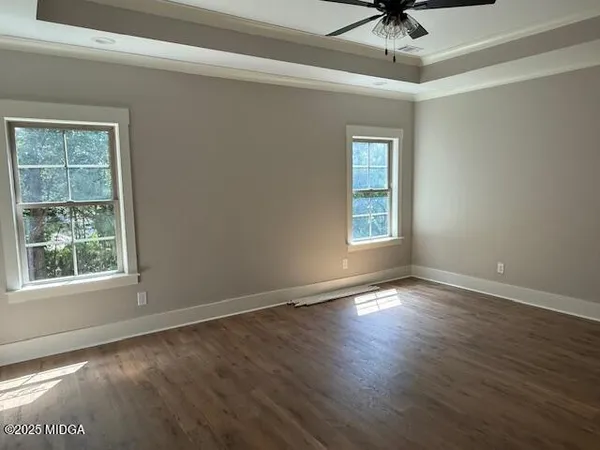 an empty room with wooden floor chandelier fan and windows