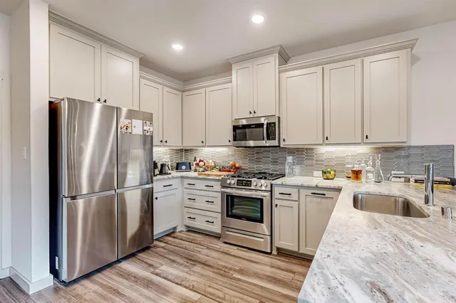 a kitchen with cabinets stainless steel appliances and wooden floor