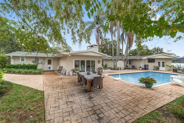 an aerial view of a house with swimming pool and large trees