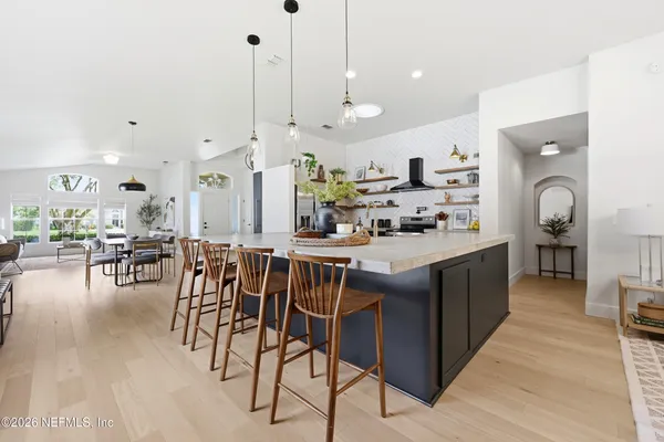 a kitchen with stainless steel appliances kitchen island granite countertop a table chairs and a stove