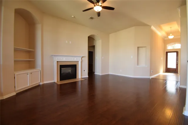 a view of an empty room with a fireplace and wooden floor