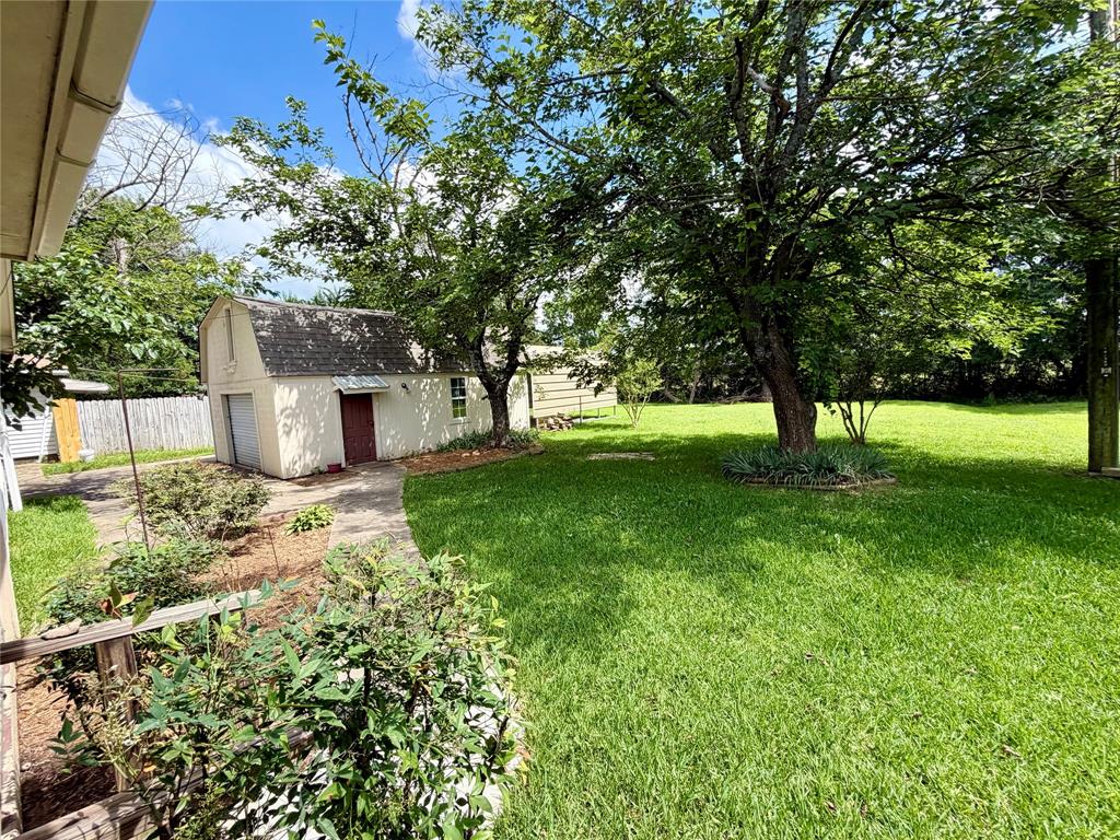 2030 Sycamore Street Paris, TX 75460 - Photo 22 of 24 Spacious backyard with mature trees, a detached barn-style outbuilding, and a curved paved pathway