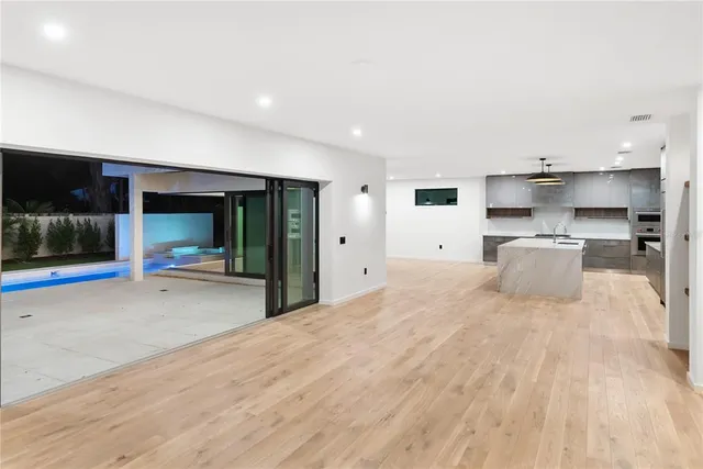 a view of an empty room with wooden floor and windows