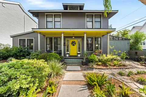 a view of a white house with large windows and a flower garden