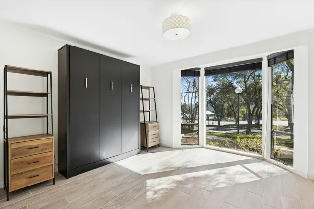 an empty room with wooden floor closet and windows